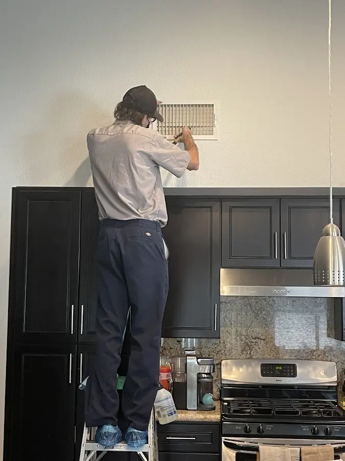 Technician inspecting an air vent during HVAC service in Albany